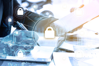 A person writing on documents at a desk, overlaid with digital padlock icons representing cybersecurity or data protection.